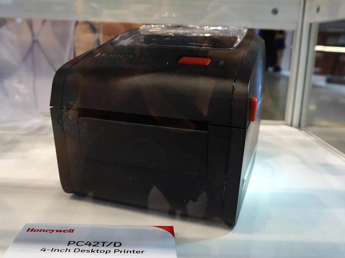 Zwarte desktop labelprinter van Honeywell, model PC42T/D, tentoongesteld in een vitrine.